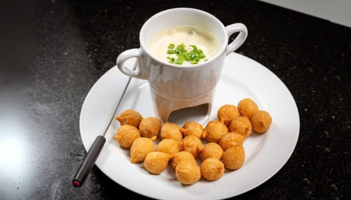 Fondue de queijo cremoso servido com petiscos fritos crocantes.