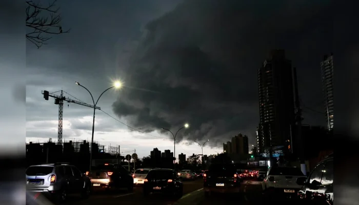 Nuvem de tempestade escura sobre trânsito urbano ao anoitecer.