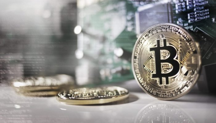 Moeda de Bitcoin física sobre fundo de placa de circuito.