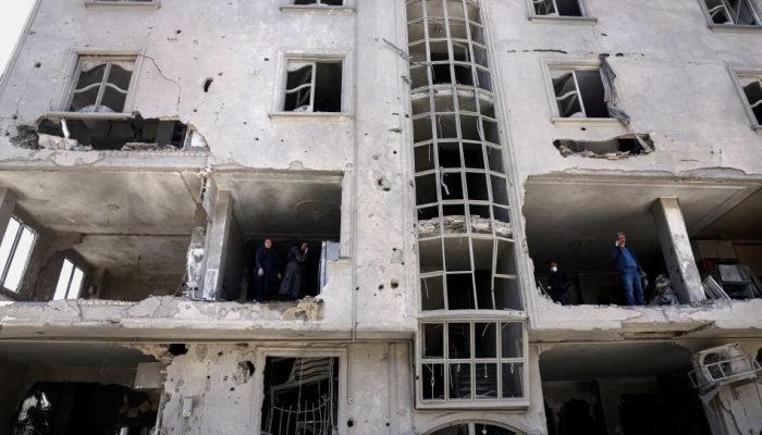 Foto: Pessoas inspecionam os danos em um prédio residencial após ser atingido po