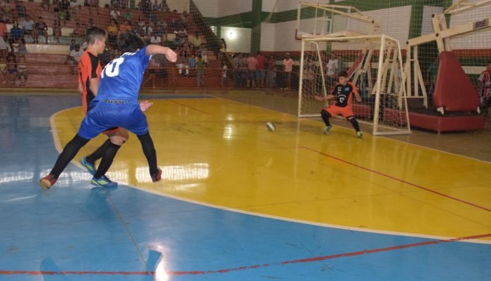 Jogador de futsal chutando a bola em direção ao gol.