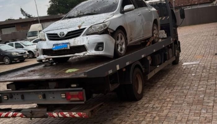 Toyota Corolla branco danificado em cima de um caminhão guincho.