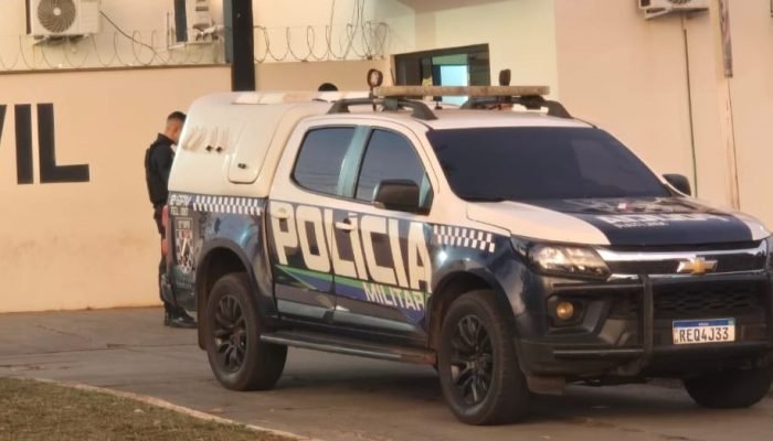 Viatura da Polícia Militar estacionada em frente a um prédio.