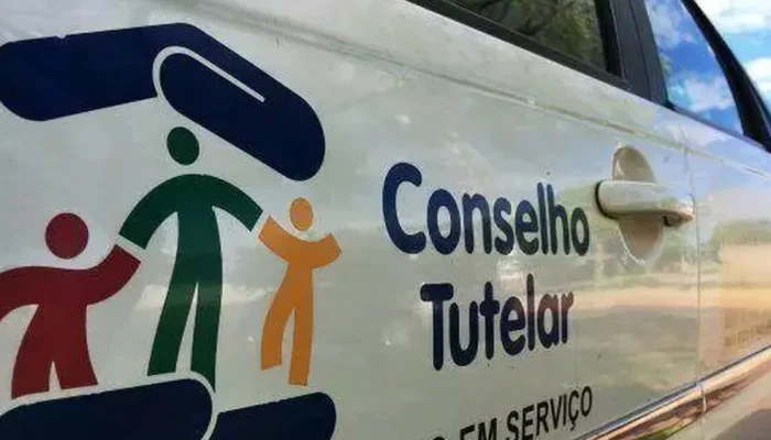 Logotipo do Conselho Tutelar na lateral de um carro branco.