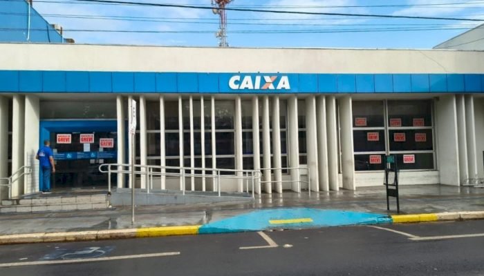 Fachada de agência da Caixa Econômica Federal com cartazes de greve.