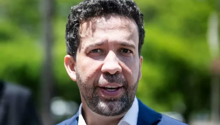Retrato de André Janones falando em um ambiente externo.