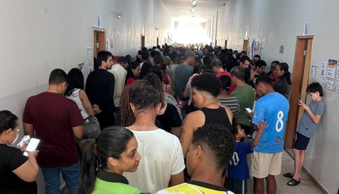 Corredor lotado com fila de pessoas aguardando atendimento.
