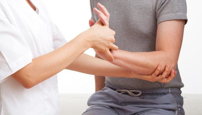 Female physiotherapist examining and massaging a hand