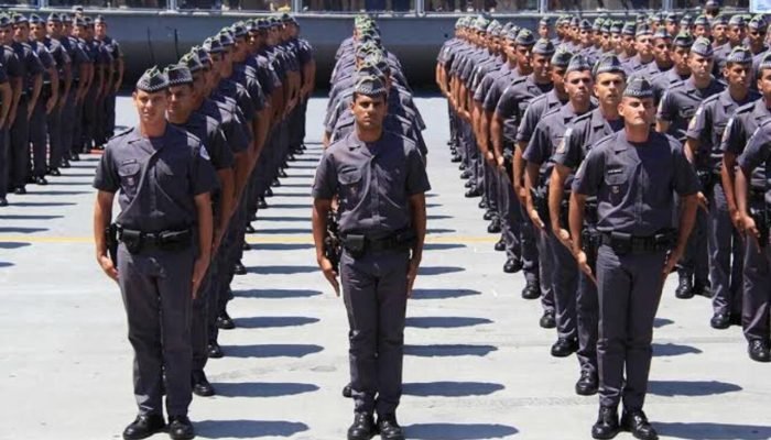 Policiais militares em formação perfilados em um pátio externo.