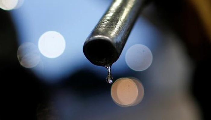 Bico de bomba de combustível com gota de líquido pendurada.