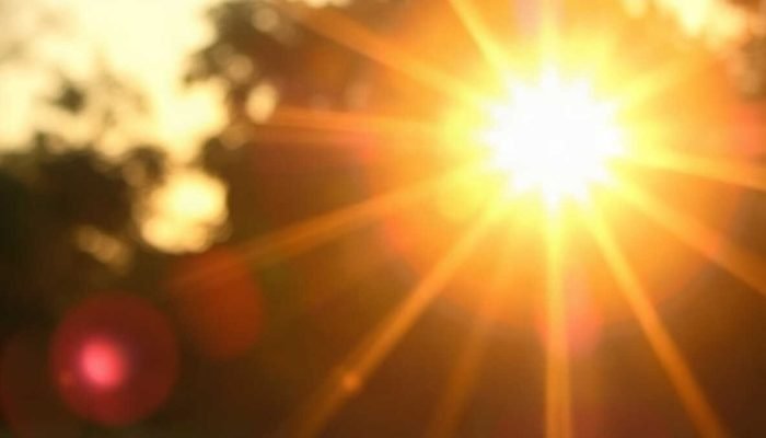 Sol brilhante com raios de luz e fundo desfocado.
