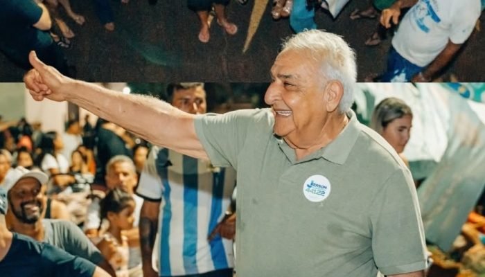 Homem sorridente em evento político com o polegar levantado.