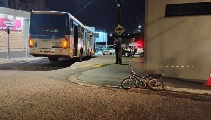 Cena de acidente noturno entre ônibus e bicicleta isolada pela polícia.