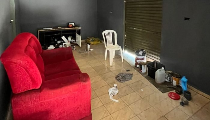 Interior de sala com sofá vermelho e materiais de pintura.
