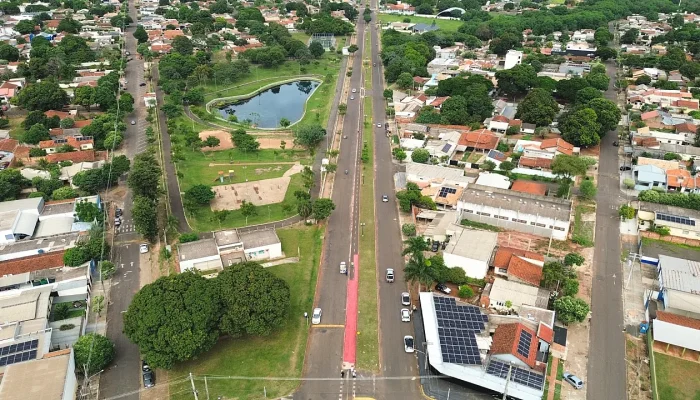 Vista aérea de avenida com ciclovia, parque e casas.