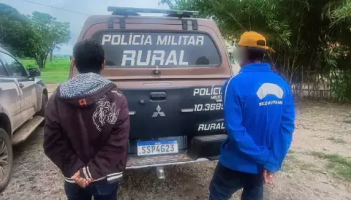 Dois homens de costas diante de uma viatura policial rural.