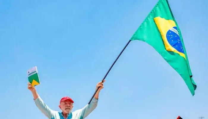 Lula segura a bandeira do Brasil e a Constituição Federal.