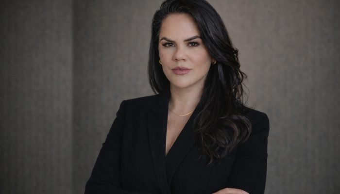 Mulher profissional de blazer preto com braços cruzados.