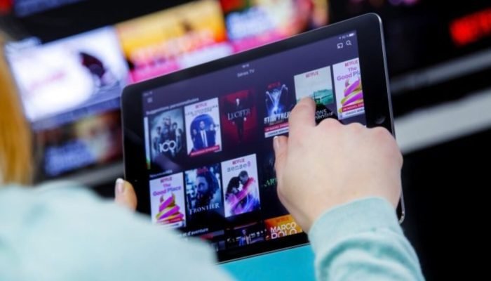Pessoa segurando tablet com o aplicativo da Netflix aberto.