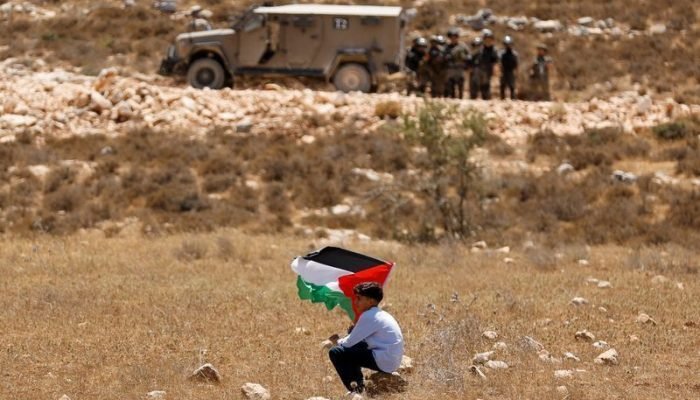 Menino com bandeira palestina durante manifestação contra o confisco de terras —