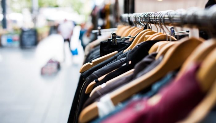 Arara de roupas com cabides de madeira em mercado externo.