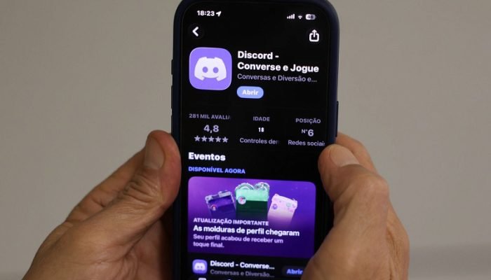 Mãos segurando celular exibindo o aplicativo Discord na loja.