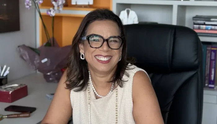 Mulher sorridente de óculos sentada em um escritório moderno.