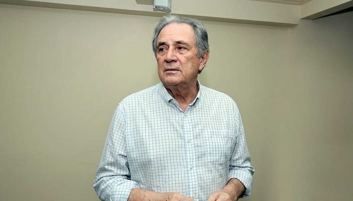 Homem idoso de camisa xadrez clara olhando para o lado.