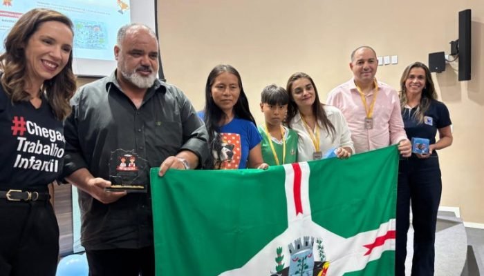 Grupo de pessoas segurando bandeira de Naviraí em premiação.
