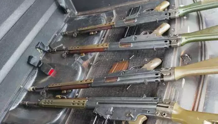 Quatro fuzis automáticos dispostos no porta-malas de um veículo.